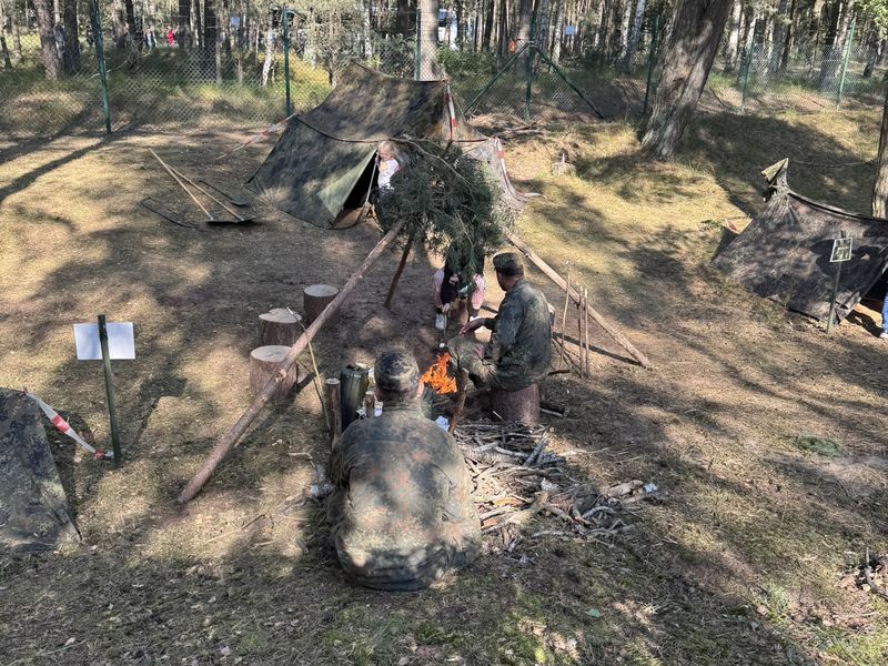 Soldaten und Kinder am Lagerfeuer vor Zelten im Kiefernwald beim Havelbiwak