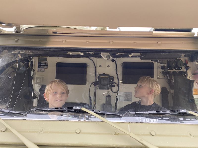 Zwei Kinder schauen aus dem Fahrerhaus eines Bundeswehrfahrzeugs