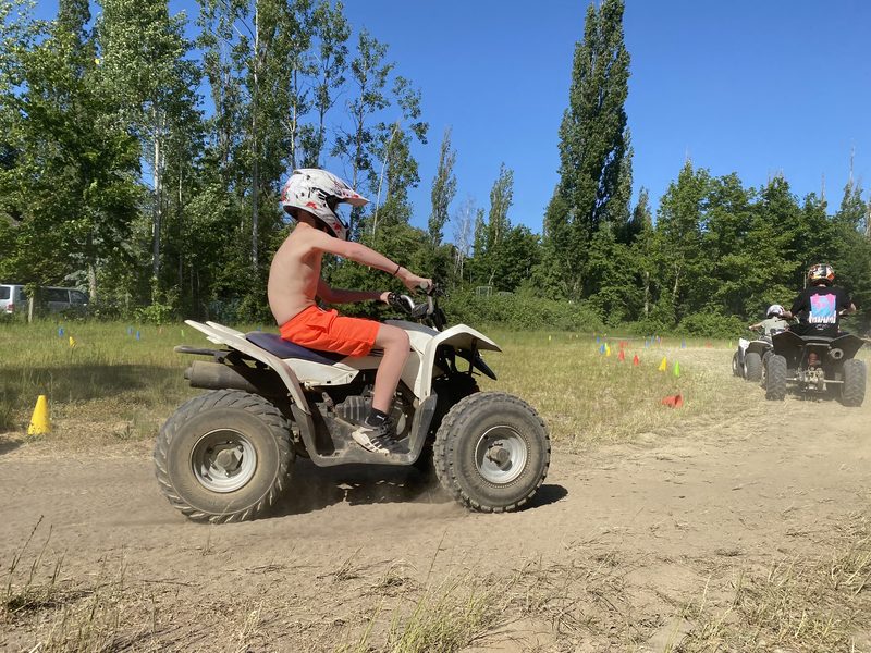 Kind mit Helm auf einem weißen Quad, weitere Fahrer voraus