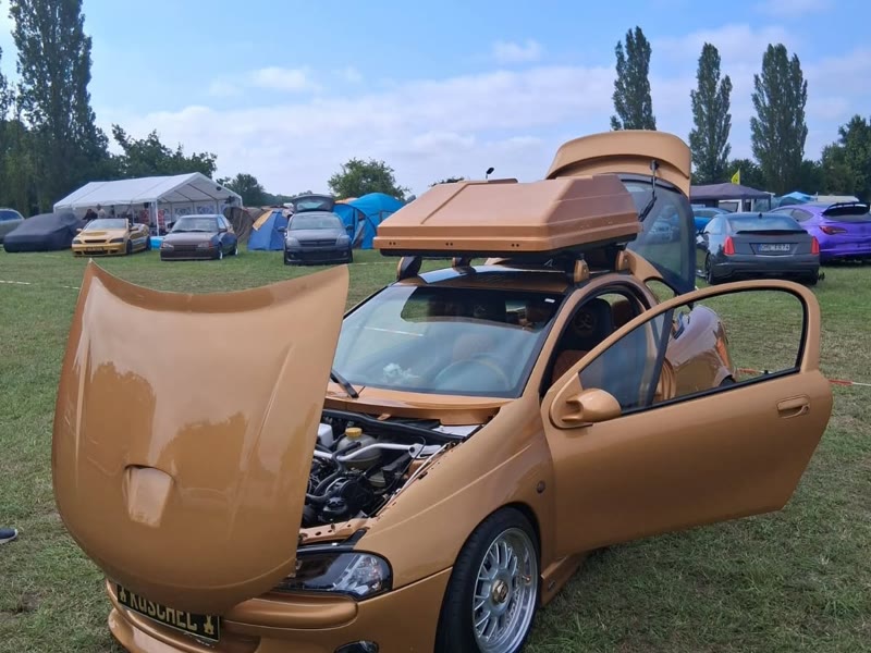 Goldener Opel mit Flügeltüren und offener Haube