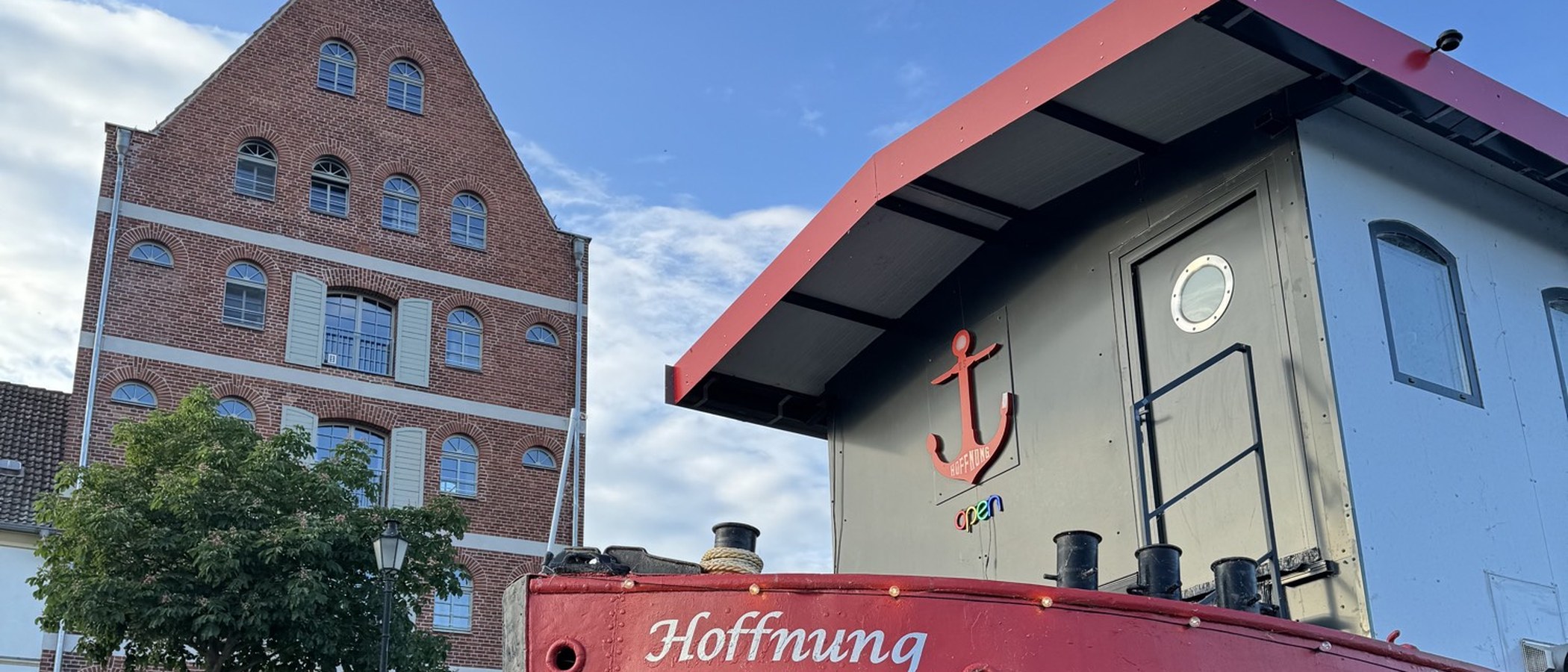 Bug des Restaurantschiffs Hoffnung mit rotem Anker und Blick zum Kornspeicher