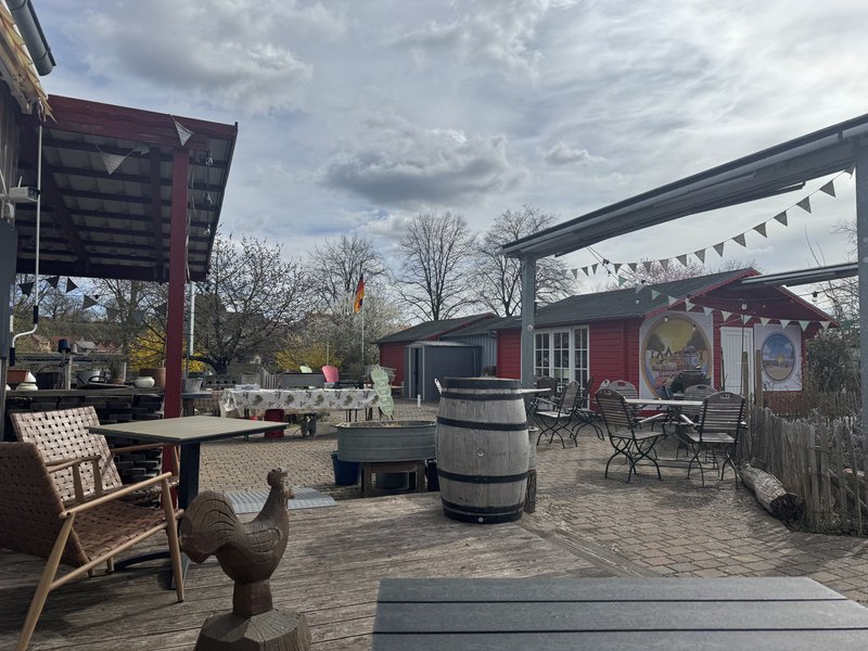 Außenterrasse Café Lieblingsplatz mit Tischen und rotem Gebäude