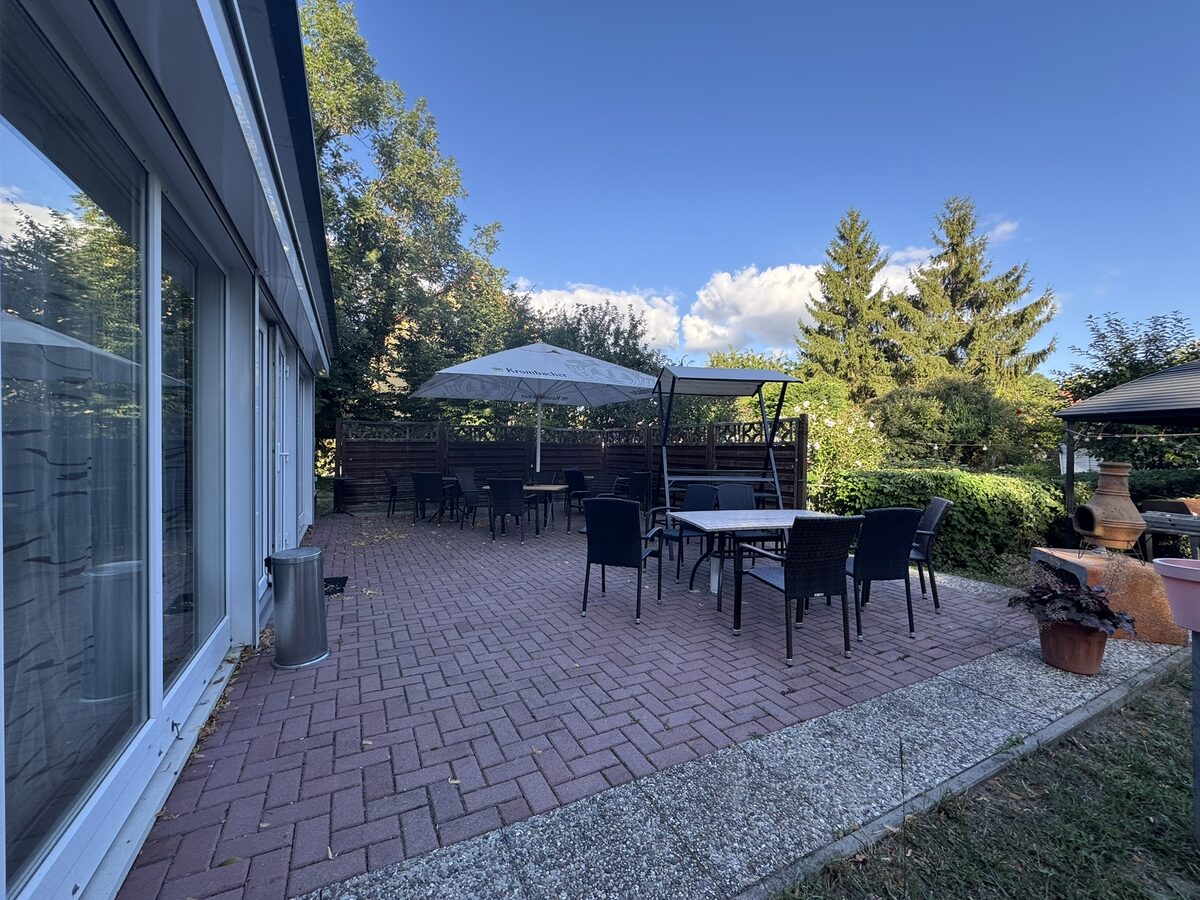 Breite Terrasse mit Sonnenschirm und Gartenmöbeln
