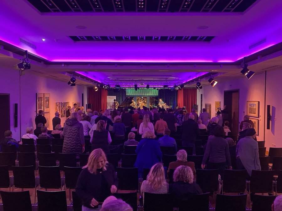 Konzertsaal im ArtHotel Kiebitzberg bei einer Live-Veranstaltung mit Publikum und Bühne unter lila Licht
