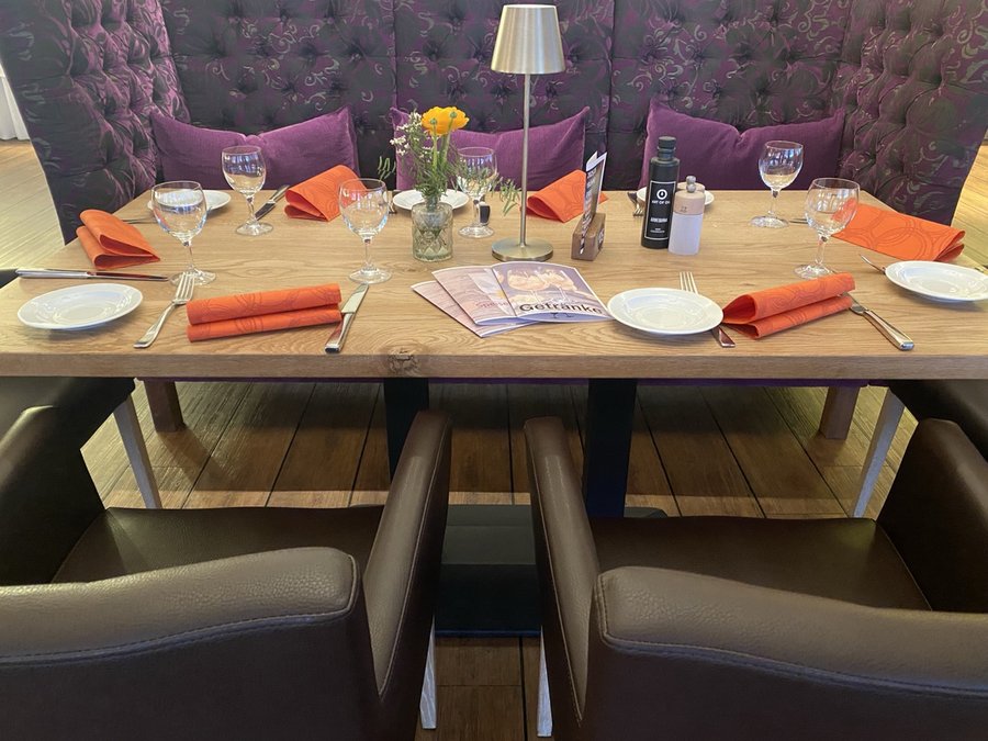 Gedeckter Tisch im Restaurant Schmokenberg mit orangen Servietten und Speisekarte